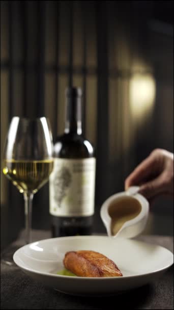 グルメサーモンステーキ スイートソース ホワイトワインとワイングラスのボトル サイドビュー ダーク雰囲気のレストラン コピースペース — ストック動画