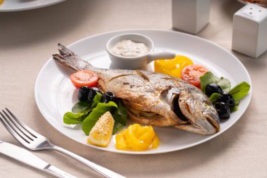 Soslu ızgara balık dorada bbq, domates ve beyaz tabakta limon. Ketogenik diyet. Sağlıklı gıda konsepti.