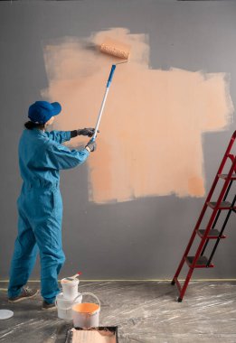 Duvarı fırçayla boyayan bir kadın ressamın arka görüntüsü. Ev yenileme konsepti. Boşluğu kopyala