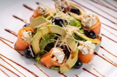 Somon salatası. Krem peynirli tuzlu somon, avokado ve beyaz tabak üzerine zeytin sosu. Kapatın. Diyet gıda konsepti