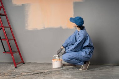 Duvarın yanında oturan kadın ressam resim yapmaya hazırlanıyor. Boşluğu kopyala