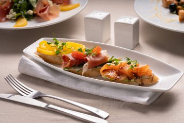 İtalyan aperatifli bruschetta tabağı doğranmış somon, jambon ve biberli ciabatta ekmeği, domates ve mikroyeşille süslenmiş. Boşluğu kopyala