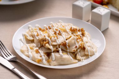 Beyaz tabakta kızarmış soğanla servis edilen patatesli hamur tatlısı. Varenyky, vareniki, pierogi. Yakın plan.