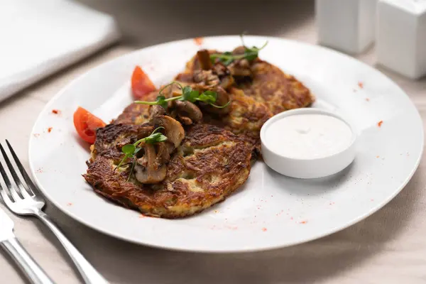 Potato pancakes with mushrooms. Potatoes pancakes on white plate with sour cream. Copy space for text. Copy space