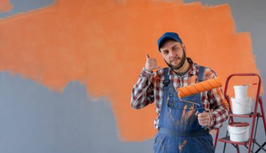 Ressam duvarın önünde duruyor ve arka tarafı işaret ediyor. Elleri ve başparmakları havada, kendinden emin. Boşluğu kopyala.