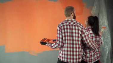 Yeni evliler yeni bir evde onarım yapıyorlar. Duvarı boya silindiriyle boyayın. Dikiz aynasından sarılmalar. Boşluğu kopyala