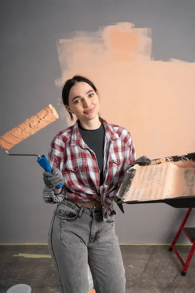 Smiling young woman painting wall of home. Renovation, repair and redecoration concept.