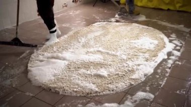 Profesyonel halı temizliği kavramı. İşçi temizlik yaptıktan sonra kirli halıyı köpükle temizler. Yakın plan.