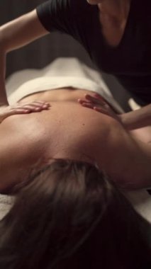 Masör elleri kaplıca merkezindeki kadına sırt masajı yapıyor. Uzayı kopyala Kaplıca salonunda estetik masaj kavramı
