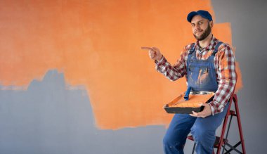 Erkek ressam, yazı için parmağını uzattı. Merdivende, yenilenmiş bir odada oturuyor. Boşluğu kopyala