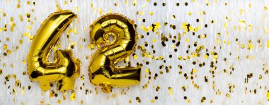 Altın folyo balon numarası, konfeti arka planında 42 numara. 42. yaş günü kartı. Yıldönümü konsepti. Doğum günü, yeni yıl kutlaması. afiş, boşluğu kopyala.