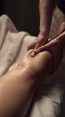 Kadın bir müşterinin bacaklarına anti-selülit masajı yapan masaj terapisti. Spa salonunda selülit önleyici masaj prosedürü. Yakın plan.