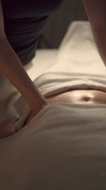 Olgun şişman kadın karın masajı yaptırıyor. Masör spa salonunda kadın midesine masaj yapıyor. Yakın plan.