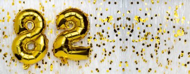 Altın folyo balon numarası, 82. 82 yazısıyla birlikte doğum günü tebrik kartı. Yıldönümü kutlaması. Pankart. Altın rakamlı, beyaz arkaplan. Sayısal rakam. Boşluğu kopyala