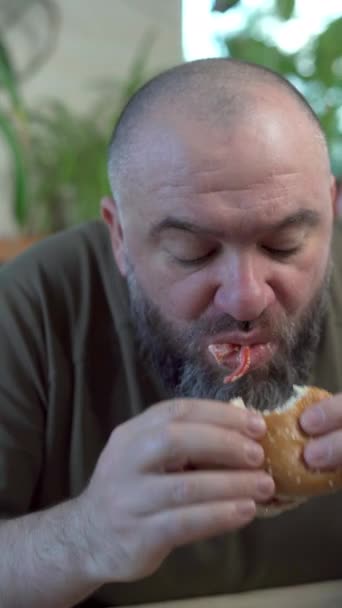 留胡子的男人在咖啡店里吃着一个大汉堡 里面有肉 — 图库视频影像