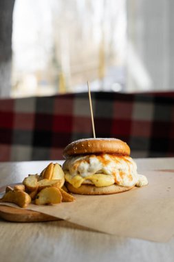Büyük hamburger ya da çizburgerle patates kızartması, kafenin içindeki ahşap tabakta servis ediliyor. Seçici bir odak noktası. Boşluğu kopyala