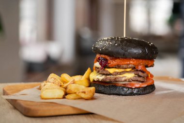 Patty, Ketçap ve çedar peynirli tahtanın üzerinde çörek ekmeğinde nefis Black Beef Burger. Fast Food Restoran konsepti