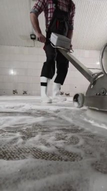 Kimyasal köpüklü halı temizleyen erkek işçi. Profesyonel disk makinesiyle halı temizleme. Uzayı kopyala, dikey video