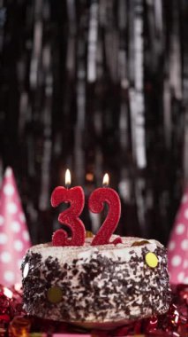Pastada 32 numaralı mumları yakmak. Otuz ikinci yaş günü pastası. Ağır çekim. Uzayı kopyala Dikey görünüm