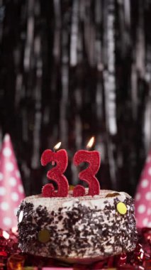 Pastada 33 numaralı mumları yakmak. 33 yaş için doğum günü pastası. Ağır çekim. Uzayı kopyala Dikey görünüm