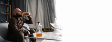 Bağımlılık bağımlılığı ve alkolizm konsepti. Üzgün alkolik adam evde oturup viski içiyor, depresif sarhoş insan sorun yaşıyor, hayattaki sorunlardan muzdarip. Pankart