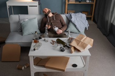 İçtikten sonra. Sarhoş sakallı adam kanepede oturuyor ve alkol aldıktan sonra uyuyor, yüksek açı. Boşluğu kopyala