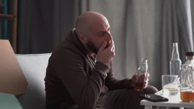 Evde alkol alan bir adam. Alkol bağımlılığı. Bunaltıcı düşünceler. Alkol bağımlılığı sorunu konsepti. Boşluğu kopyala