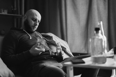 Üzgün, alkolik, alkolik, evde tek başına viski içen alkolik, alkolik, alkol bağımlılığı sorunu olan bağımlı bir adam. Alkolizm konsepti. Siyah beyaz fotoğraf