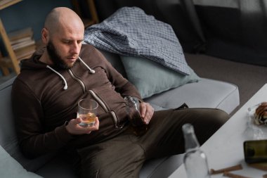 Alkolizm, alkol bağımlılığı ve insan konsepti. Alkolik bir adam bir bardak viskiyle kanepede uyuyor. Boşluğu kopyala