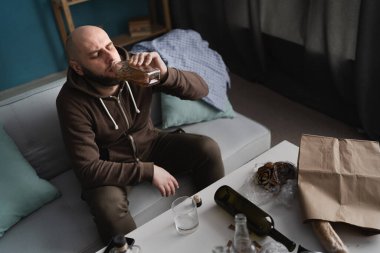 Evde kanepede oturmuş viski içen yalnız erkek alkolik. alkolizm, alkol bağımlılığı ve insanlar konsepti.