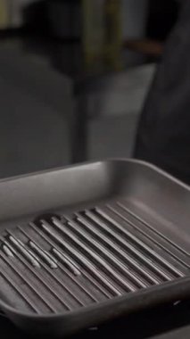 Şef, biberiye ve sarımsaklı zeytinyağında kızartılmış ton balığı bifteği pişiriyor. Uzayı kopyala Dikey video