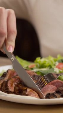 Restoranda yemek yiyen kadın. Çatal ve bıçakla biftek yemek. Yakın plan. Dikey görünüm
