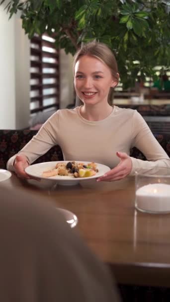 レストランでロマンチックな昼食の日に金髪の女性を笑う カフェテーブルで笑顔の魅力的な少女 ファインダイニングコンセプト パブリック バーティカルビデオ — ストック動画