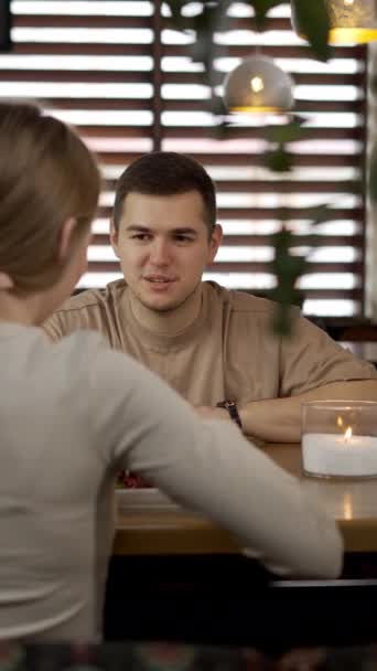 ハッピーカップルは レストランで屋内に座り 話したり 昼食をとったりしています バーティカルビデオ — ストック動画