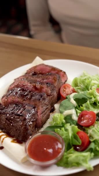 Krojony Stek Wołowy Grilla Talerzu Sałatą Pomidorami Służący Stole Restauracyjnym — Wideo stockowe