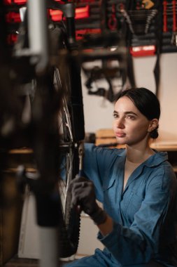 Bisikletli kadın tamirci, tamirci, profesyonel işini atölyede ya da garajda yapıyor. Yakın plan.