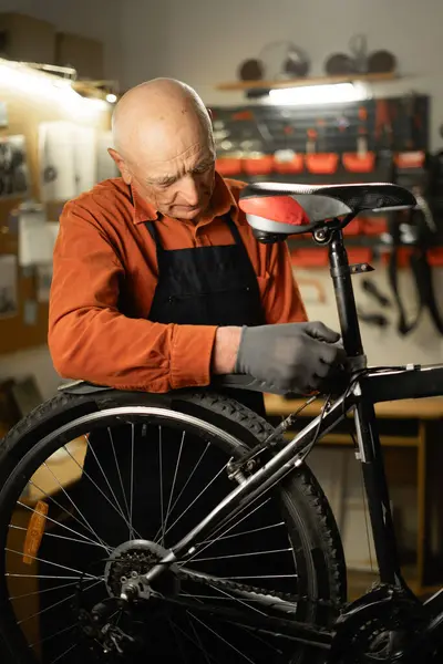Old repairman, bike maintenance and fixing saddle, self bike workshop at home. Copy space