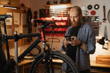 Bir bisiklet tamir atölyesinde tamirci akıllı telefon kullanarak mesaj okuyor ya da internetten bisikletle ilgili bilgi arıyor. Boşluğu kopyala