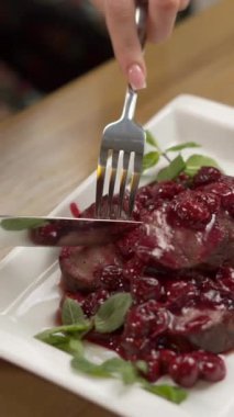 Beyaz tabakta kiraz soslu biftek. Orta pişmiş, kiraz soslu biftek yiyen bir kadın. Restoran menüsü. Üst görünüm