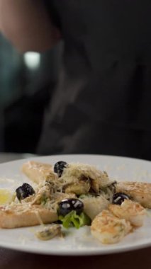 Profesyonel şef zeytin, sıcak karides ve balık salatası, deniz ürünleri ve sağlıklı gıda konseptiyle dekore ediyor. Yakın plan. Menü ve yemek tarifi kitabı. Dikey video