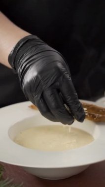 Restoran mutfağında peynirli kremalı çorba tabağı olan bir erkek şef. Yemek pişirme, meslek ve insan konsepti. Dikey video