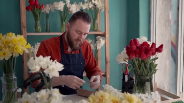 有魅力的花匠在工作场所做花束的肖像 聚精会神的大胡子男人坐在花店里 复制空间 — 图库视频影像