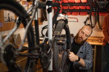 Bisiklet servisi, tamir ve geliştirme konsepti. Bisiklet tamircisi atölyede bisiklet tekerleğini tamir ediyor. Bisiklet tamircisi. Boşluğu kopyala