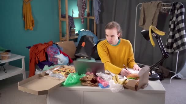 Mannelijke Student Studeert Een Rommelige Kamer Maakt Aantekeningen Tussen Vuilnis — Stockvideo