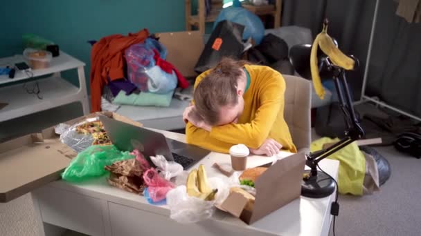うんざりした生徒が家でテーブルで寝ている 若い男は家で働く疲れ果てた男だった ラップトップを使用したフリーランサー フリーランスワーク ストレスコンセプト — ストック動画