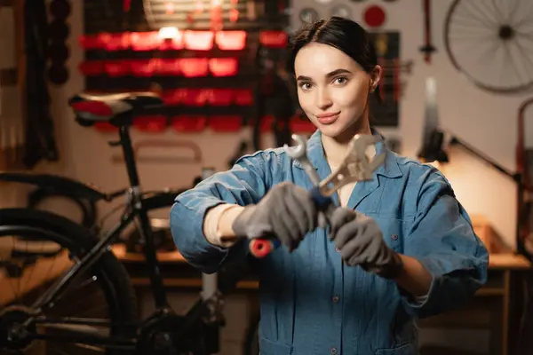 Bicycle care maintenance and servicing concept. Portrait of female technician mechanic using the wrench to repairing bike service support in garage or repair workshop. Copy space