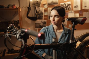 Bisiklet atölyesindeki portre tamircisi kadın. Garaj ve girişim. Kendine güvenen motorcu kadın tamirci. Boşluğu kopyala