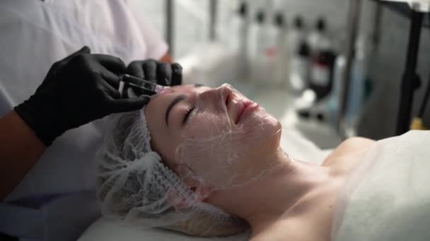 化粧品学者は 女性の顔にしわを滑らかにするための顔の注射手順を若返らせます 化粧品コンセプト コピースペース — ストック動画