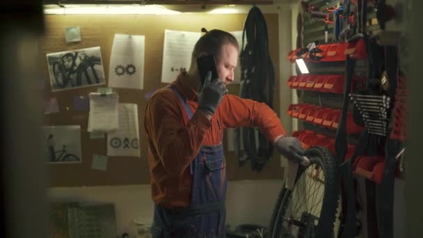 Cykelunderhåll Cykelmekaniker Pratar Med Kollegan Smartphone Ryttaren Torkar Cykeln Ren Stockfilm