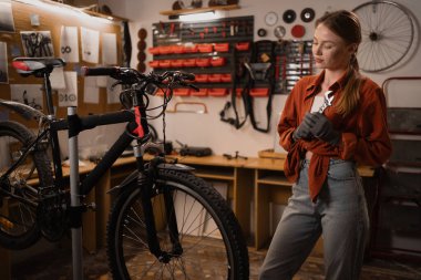 Sarışın bir kızın portresi elinde ayarlanabilir bir anahtarla bir atölyede ya da garajda bisiklet tamir ederken. Hobi ve oyun konsepti. Boşluğu kopyala